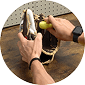 Hands apply yellow conditioner to a baseball glove. A pegboard is visible in the background.